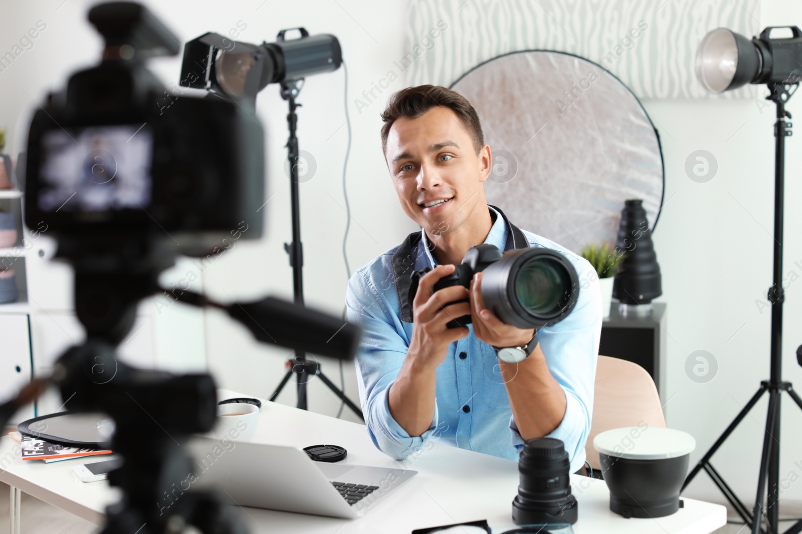 Photo of Male photo blogger recording video on camera indoors