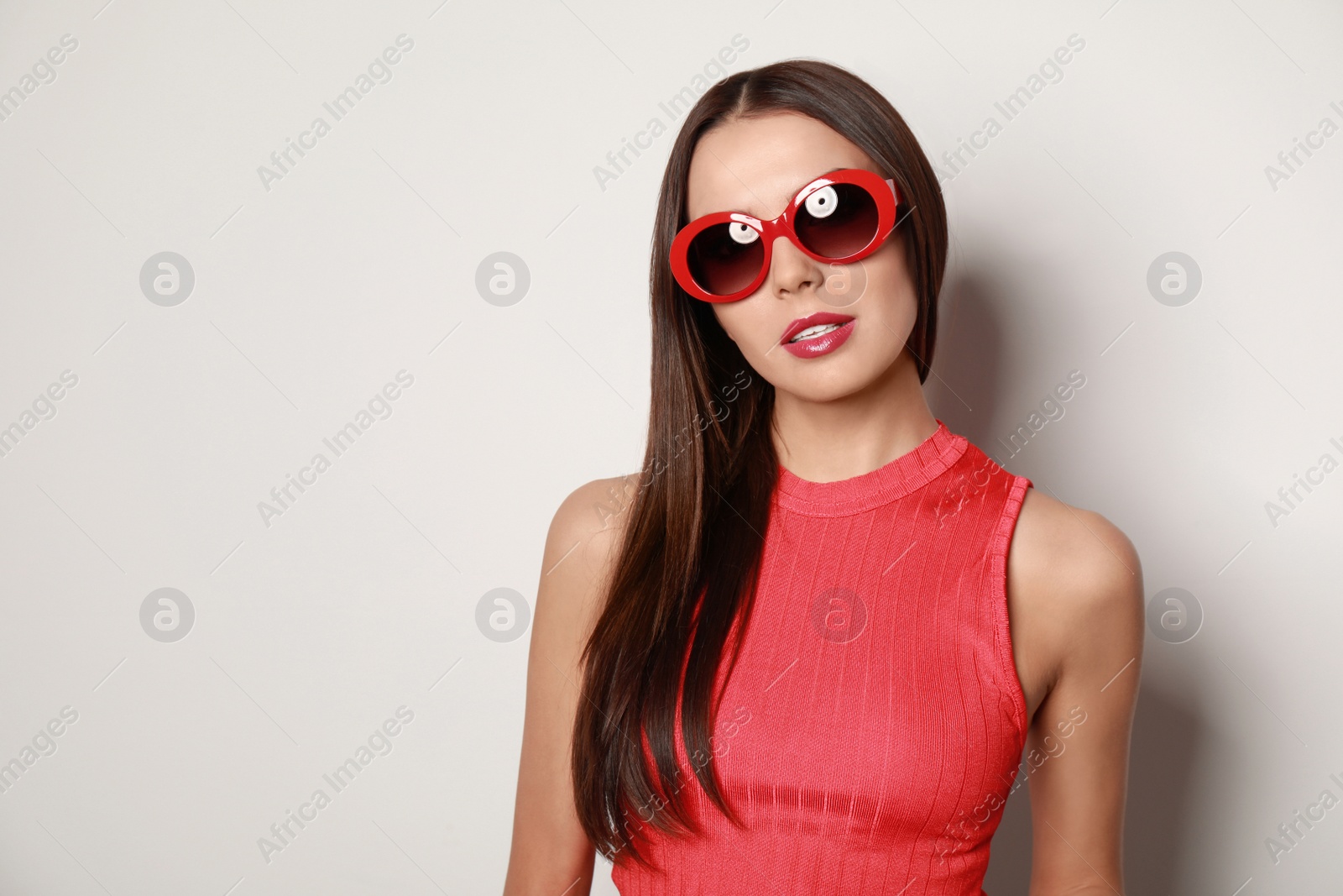 Photo of Beautiful woman in stylish sunglasses on light background, space for text