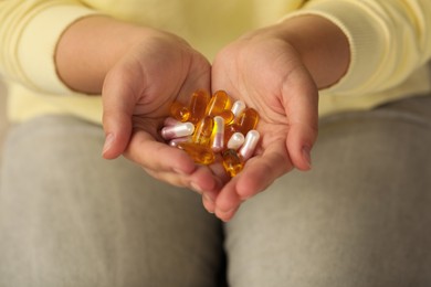 Photo of Young woman holding pile of dietary supplement pills, closeup