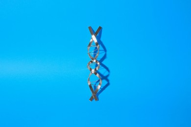 Photo of DNA molecular chain model made of metal on blue background, top view