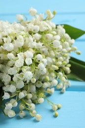 Photo of Beautiful lily of the valley bouquet on light blue wooden table, closeup