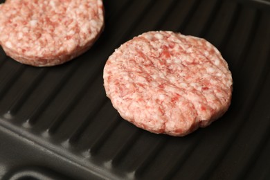 Fresh raw hamburger patties on grill pan, closeup