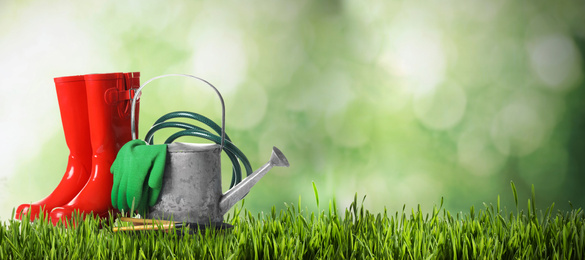 Image of Set of gardening tools on green grass against blurred background, space for text. Banner design