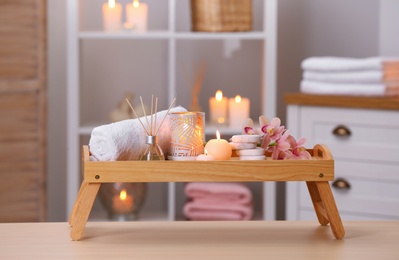 Photo of Composition with candles, flowers and stones on wooden table in spa salon