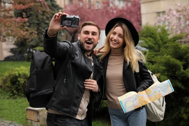 Couple of tourists with camera taking selfie on city street