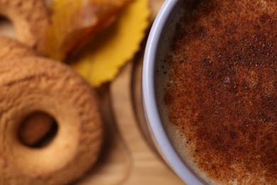 Photo of Cup of hot drink, cookies and autumn leaves on wooden board, closeup