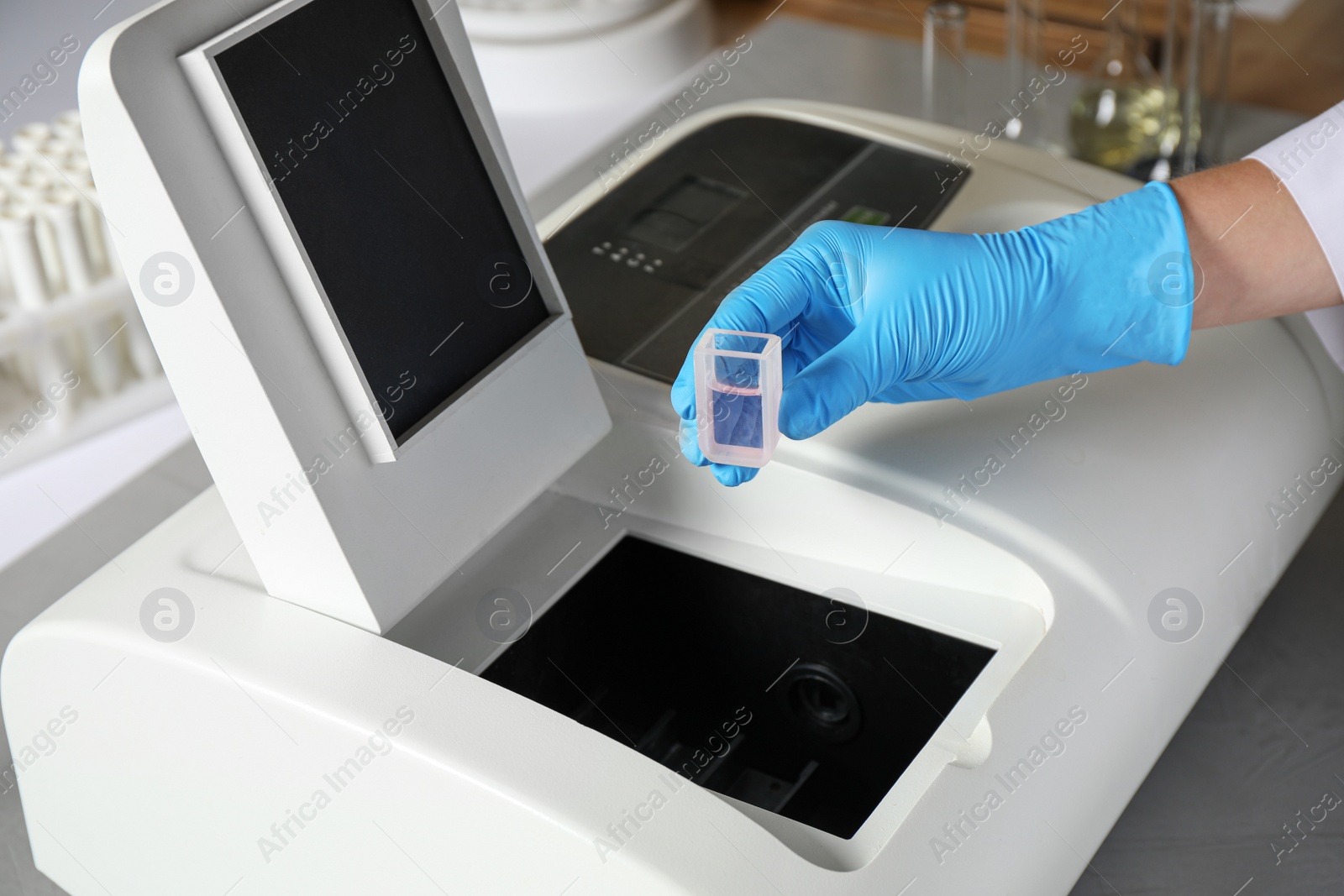 Photo of Scientist putting sample compartment with liquid in spectrophotometer, closeup. Laboratory analysis