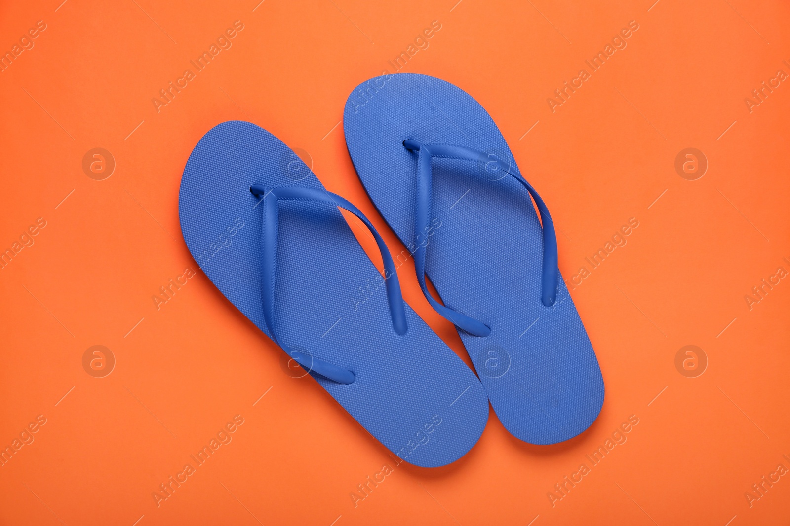 Photo of Stylish blue flip flops on orange background, top view