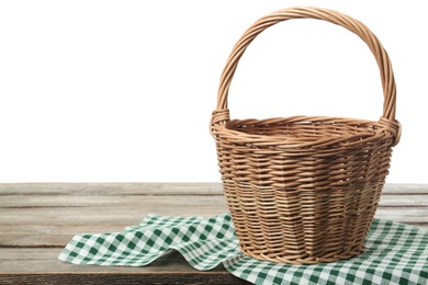 Empty wicker basket and cloth on wooden table against white background, space for text. Easter holiday