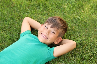 Photo of Cute little boy on green grass in park. Happy child