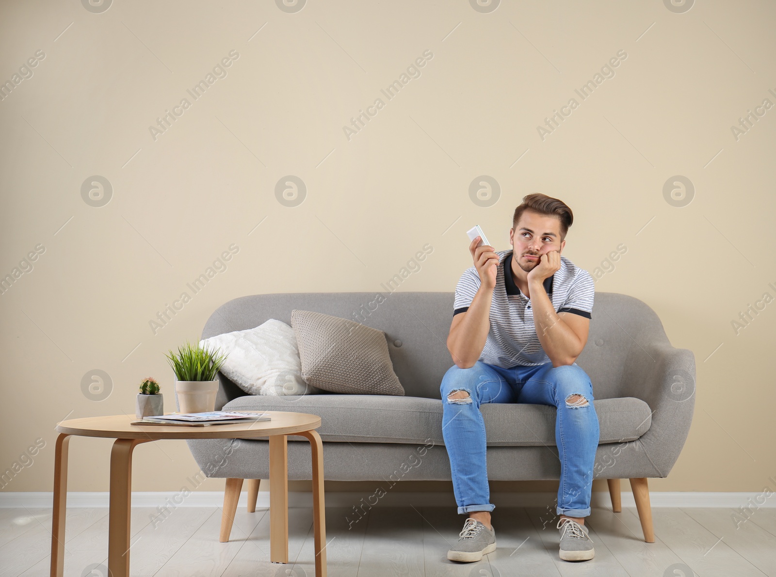 Photo of Young man with air conditioner remote at home