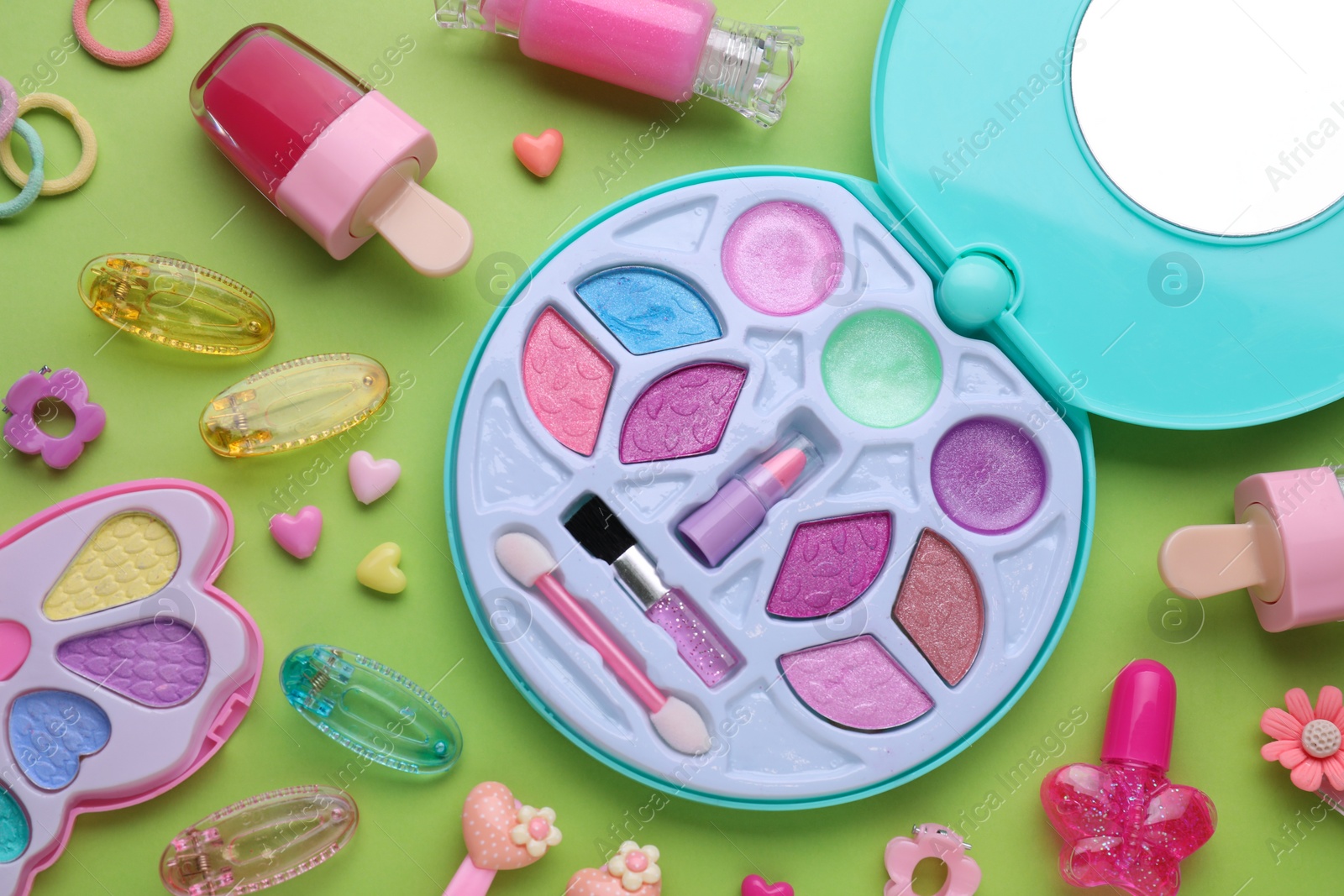 Photo of Eye shadow palette and other decorative cosmetics for kids on light green background, flat lay