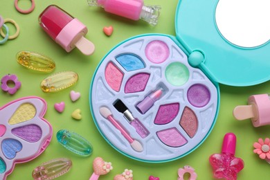 Photo of Eye shadow palette and other decorative cosmetics for kids on light green background, flat lay