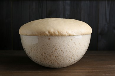 Photo of Bowl of fresh yeast dough on wooden table