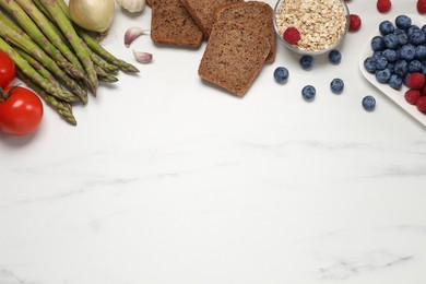 Flat lay composition with different fresh products on white marble table, space for text. Source of prebiotics