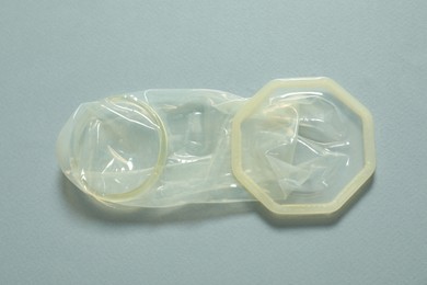 Unrolled female condom on light blue background, above view. Safe sex