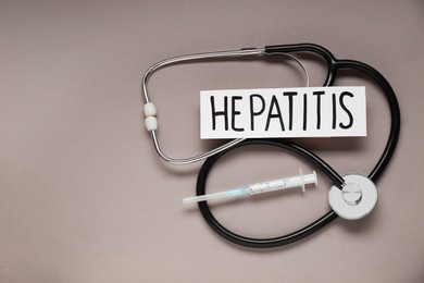 Photo of Word Hepatitis, stethoscope and syringe on beige background, flat lay. Space for text