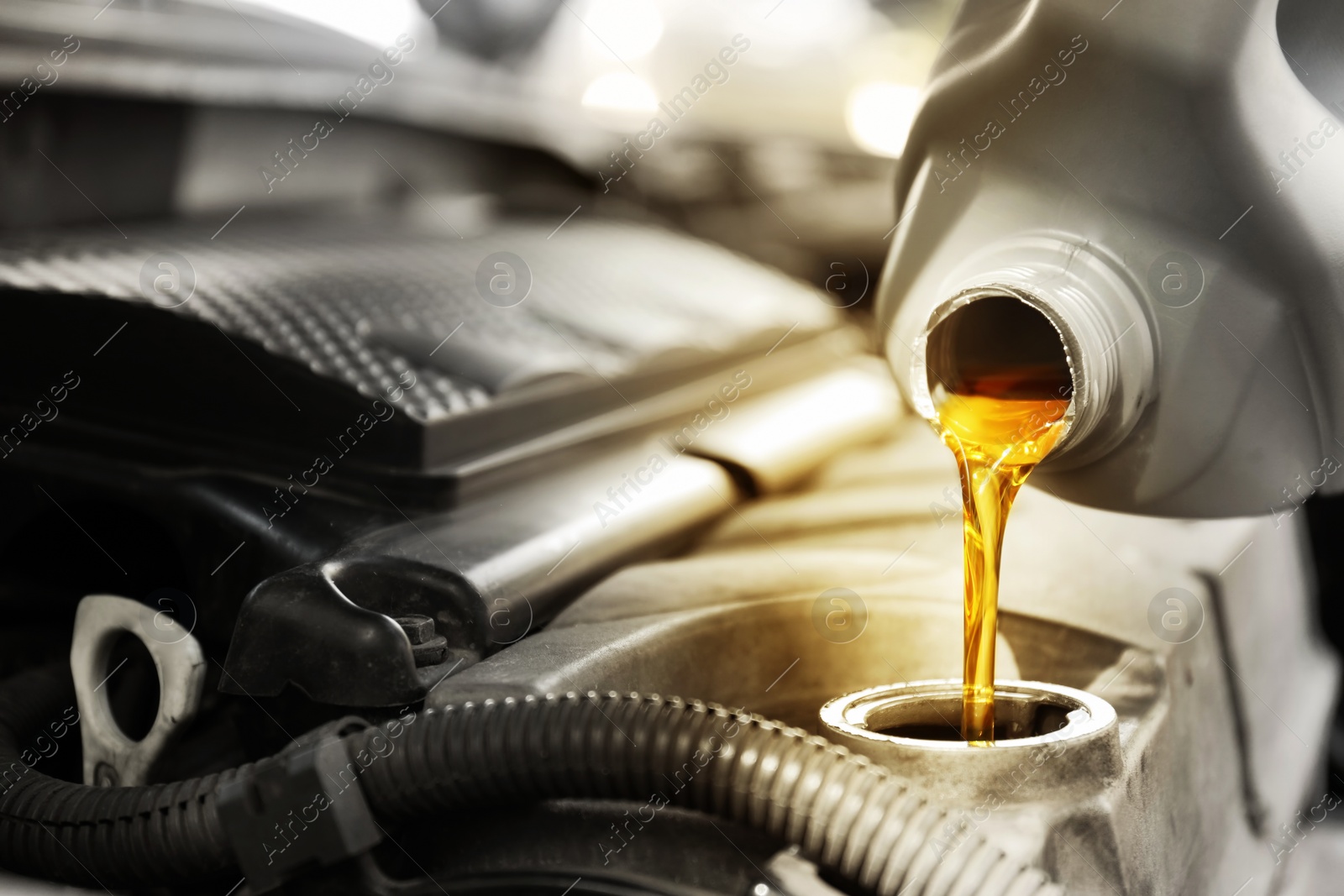 Image of Pouring motor oil into car engine, closeup. Color accent effect