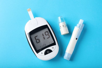 Photo of Digital glucometer and lancet pen on light blue background, flat lay. Diabetes control