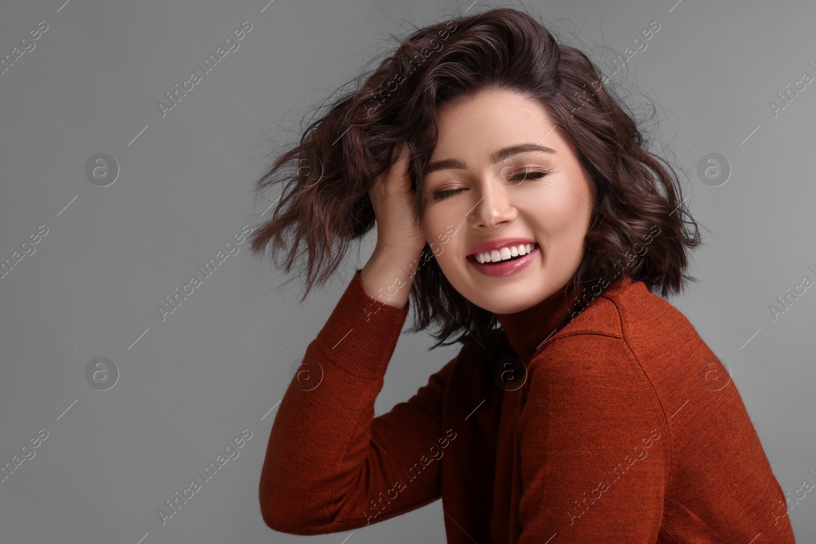 Photo of Portrait of beautiful young woman with wavy hairstyle on grey background. Space for text