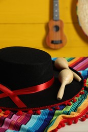 Black Flamenco hat, poncho and maracas on light table, closeup