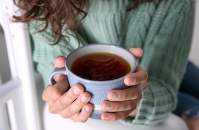 Photo of Woman with cup of hot tea indoors, closeup. Cozy home atmosphere