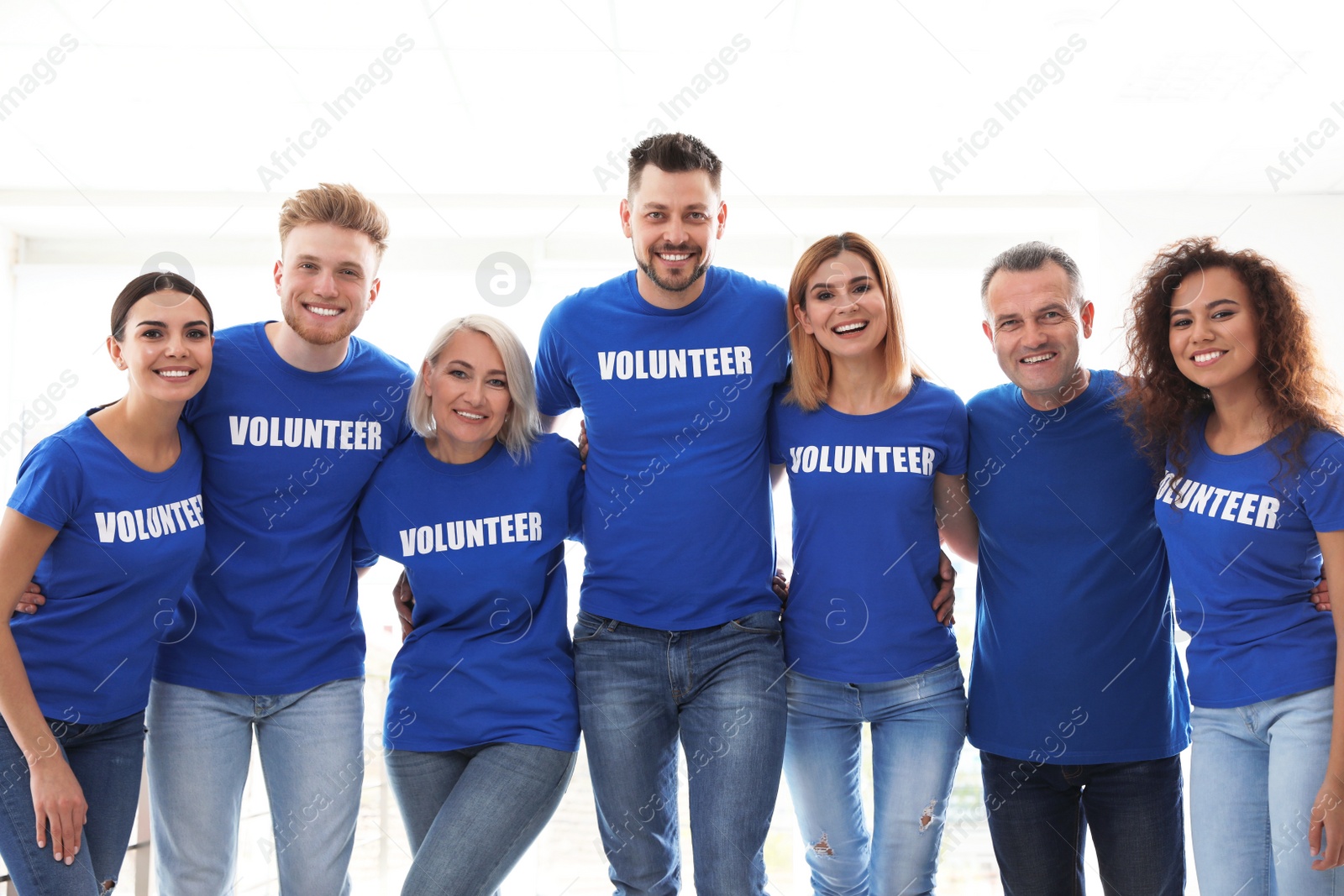 Photo of Team of volunteers in uniform on light background