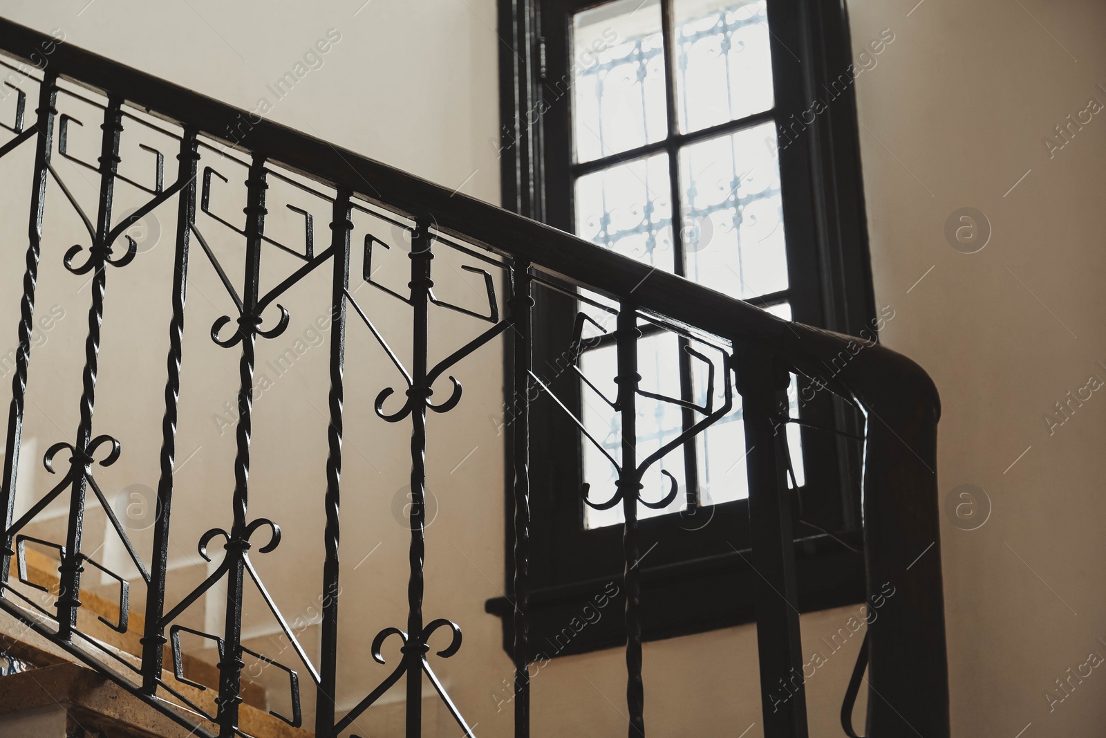 Photo of Stairs and black metal railing indoors. Interior design