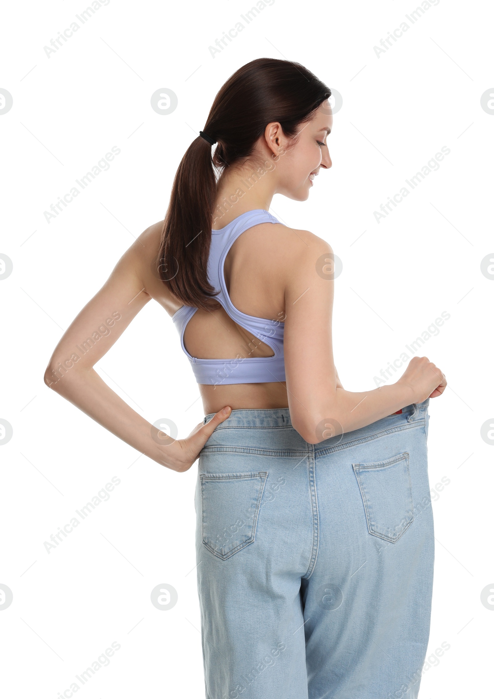 Photo of Young woman in big jeans showing her slim body on white background