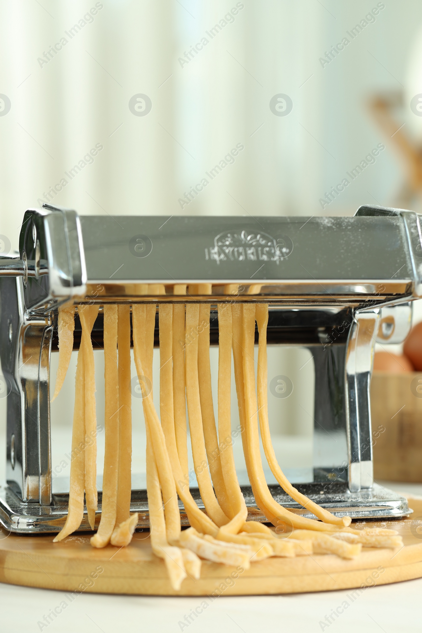 Photo of Pasta maker with raw dough on white table, closeup