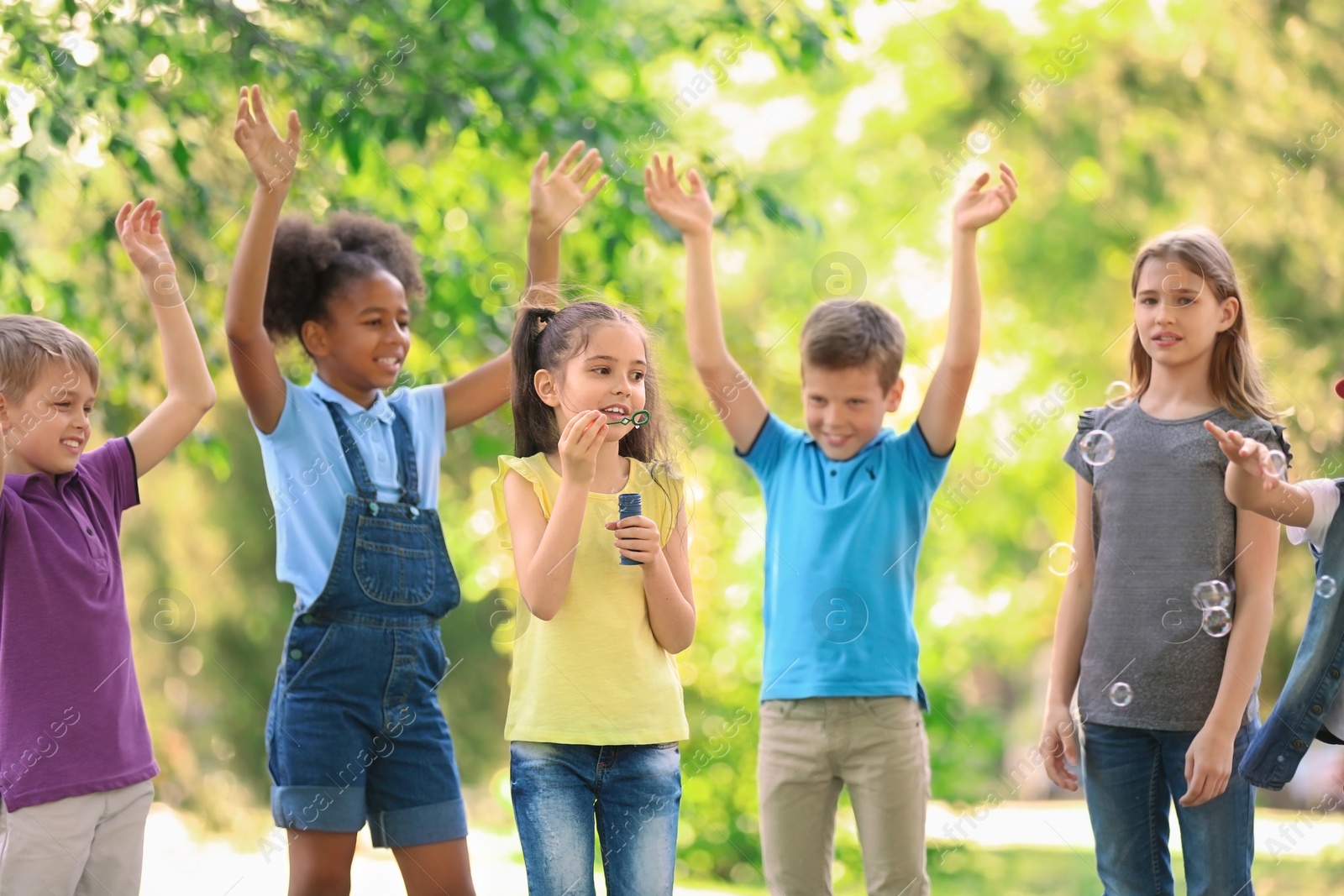 Photo of Cute little children playing with soap bubbles outdoors on sunny day