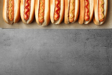 Photo of Tasty fresh hot dogs on grey background, top view. Space for text