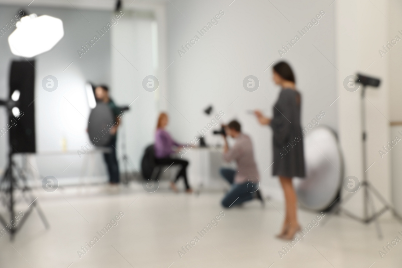 Photo of Blurred photo studio with professional equipment and team of workers