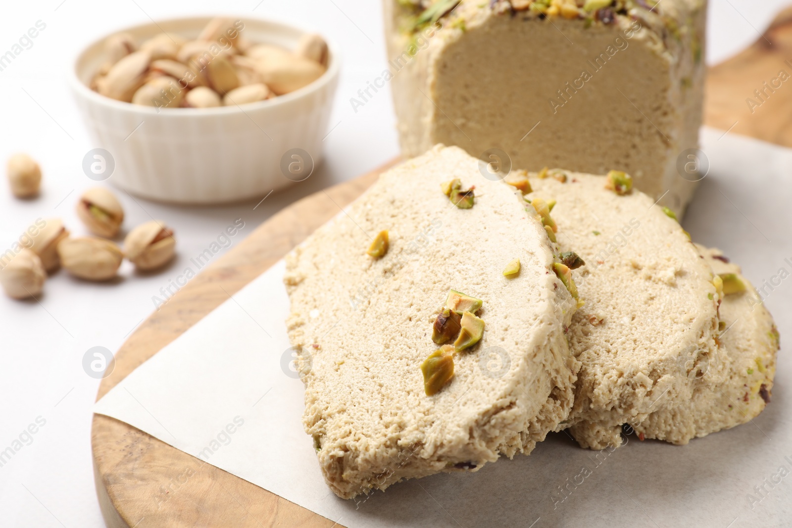 Photo of Tasty halva with pistachios on white table, closeup