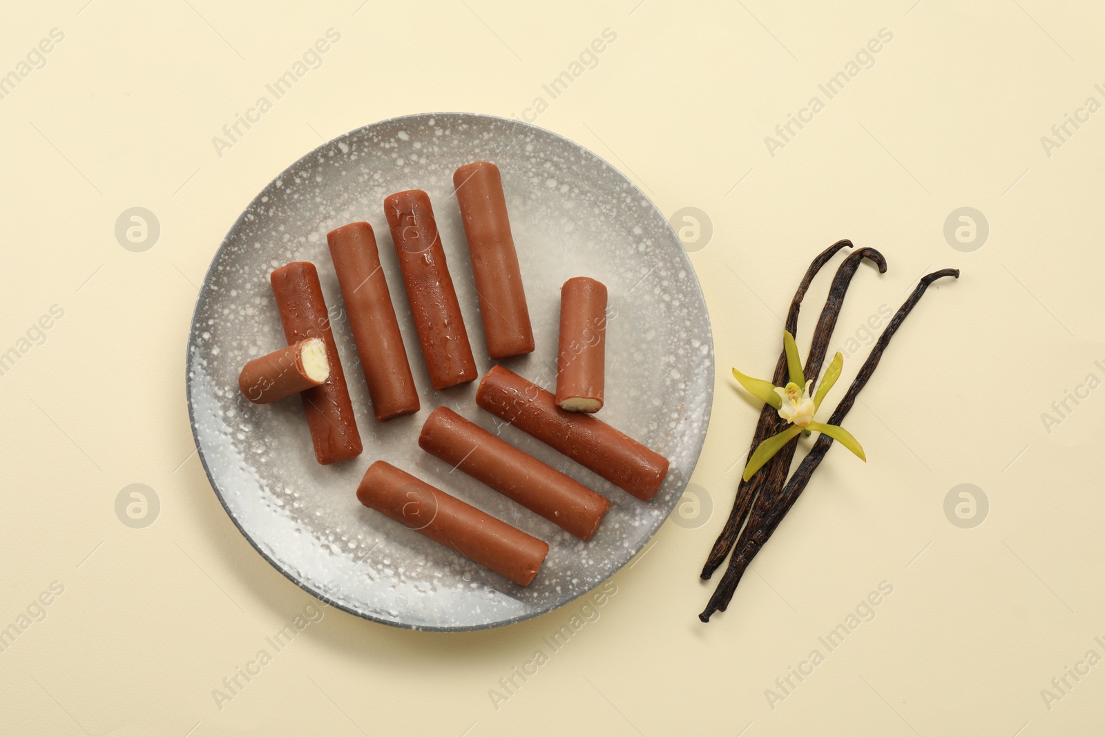 Photo of Glazed curd cheese bars, vanilla pods and flower on beige background, top view