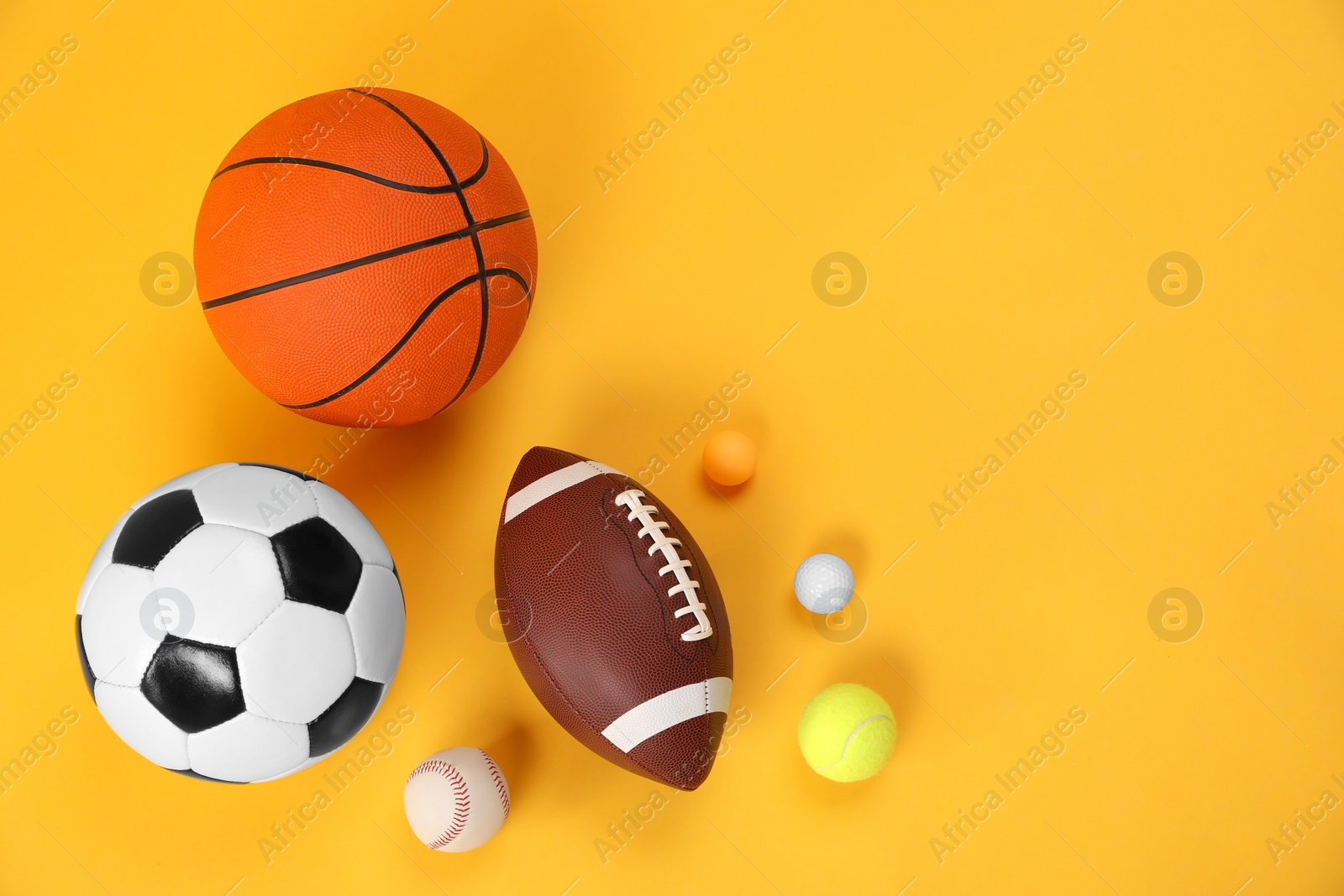 Photo of Many different sports balls on yellow background, flat lay. Space for text