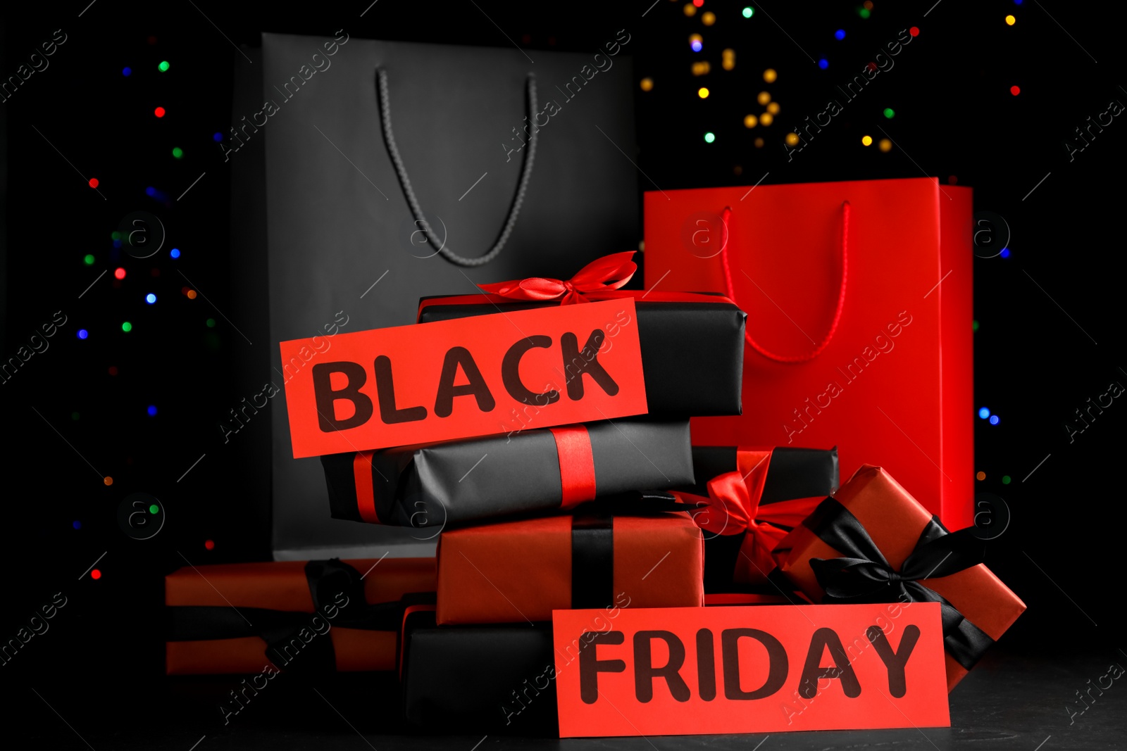 Photo of Paper shopping bags and gift boxes against blurred lights. Black Friday sale