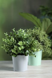 Photo of Aromatic oregano and thyme growing in pots on white wooden table outdoors