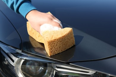 Photo of Man washing car hood with sponge, closeup