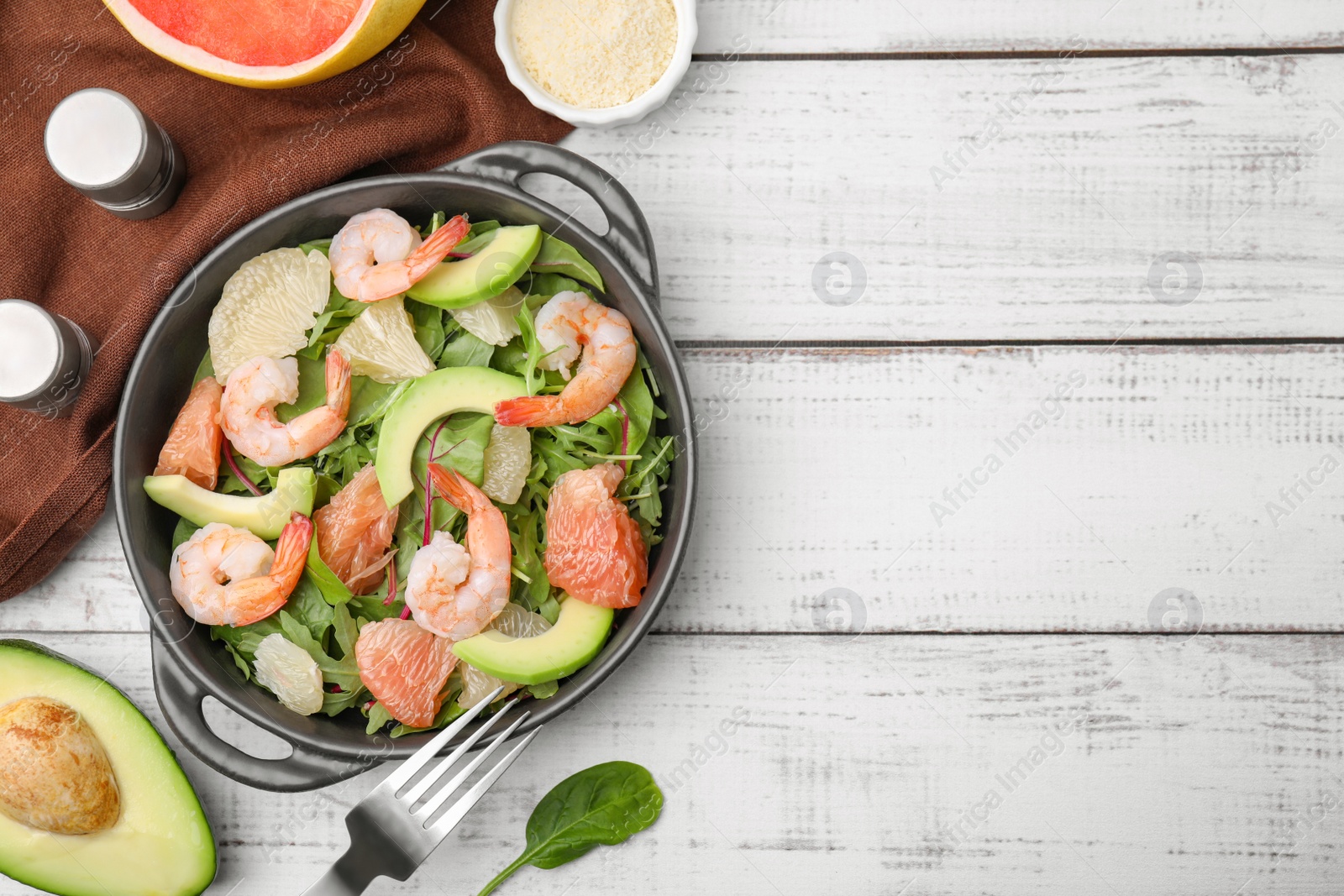 Photo of Delicious pomelo salad with shrimps served on white wooden table, flat lay. Space for text