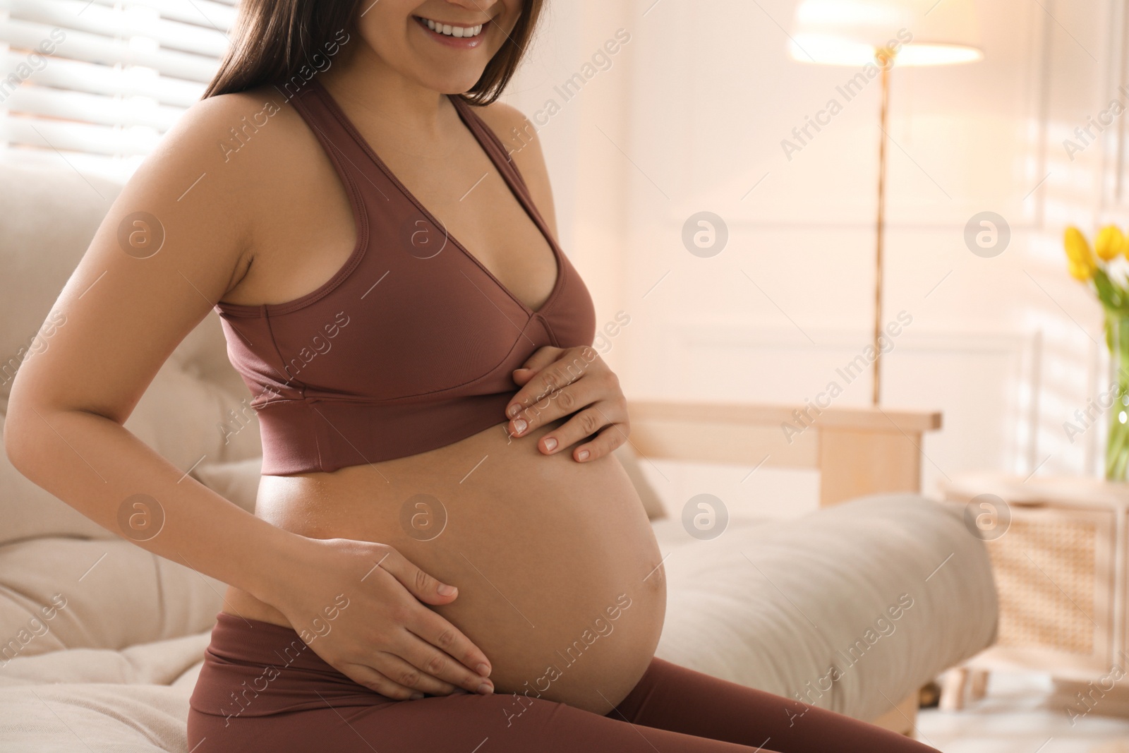 Photo of Pregnant young woman touching belly at home, closeup