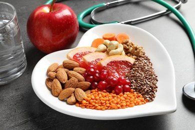 Photo of Plate with products for heart-healthy diet on grey table