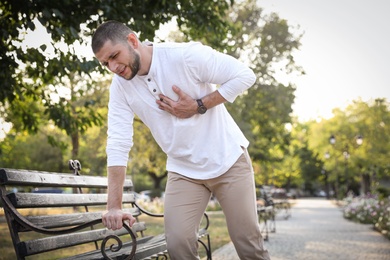 Man having heart attack near bench in park