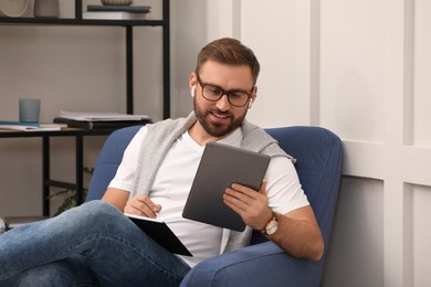 Photo of Young man with earphones working on tablet at home