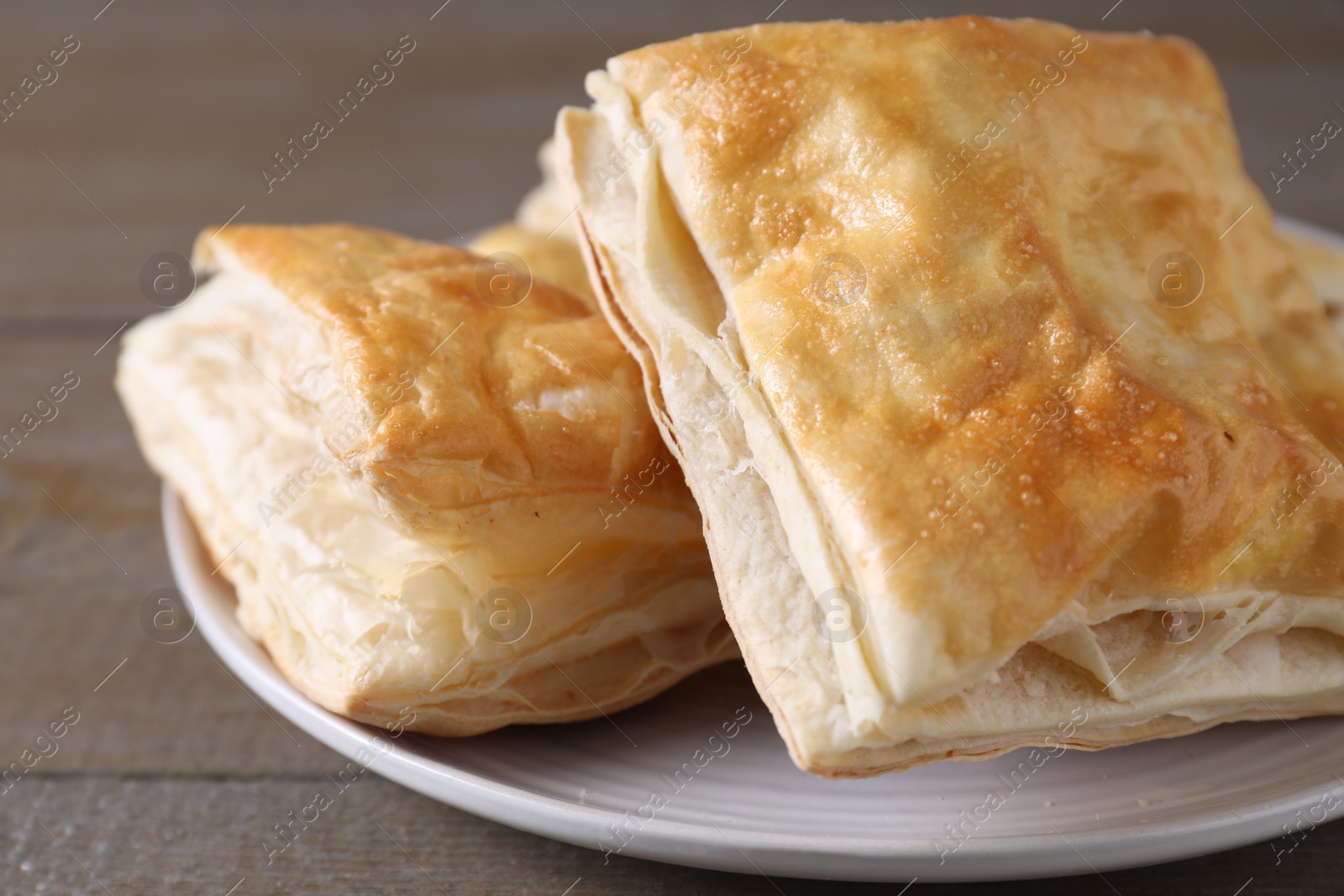 Photo of Delicious fresh puff pastries on wooden table, closeup