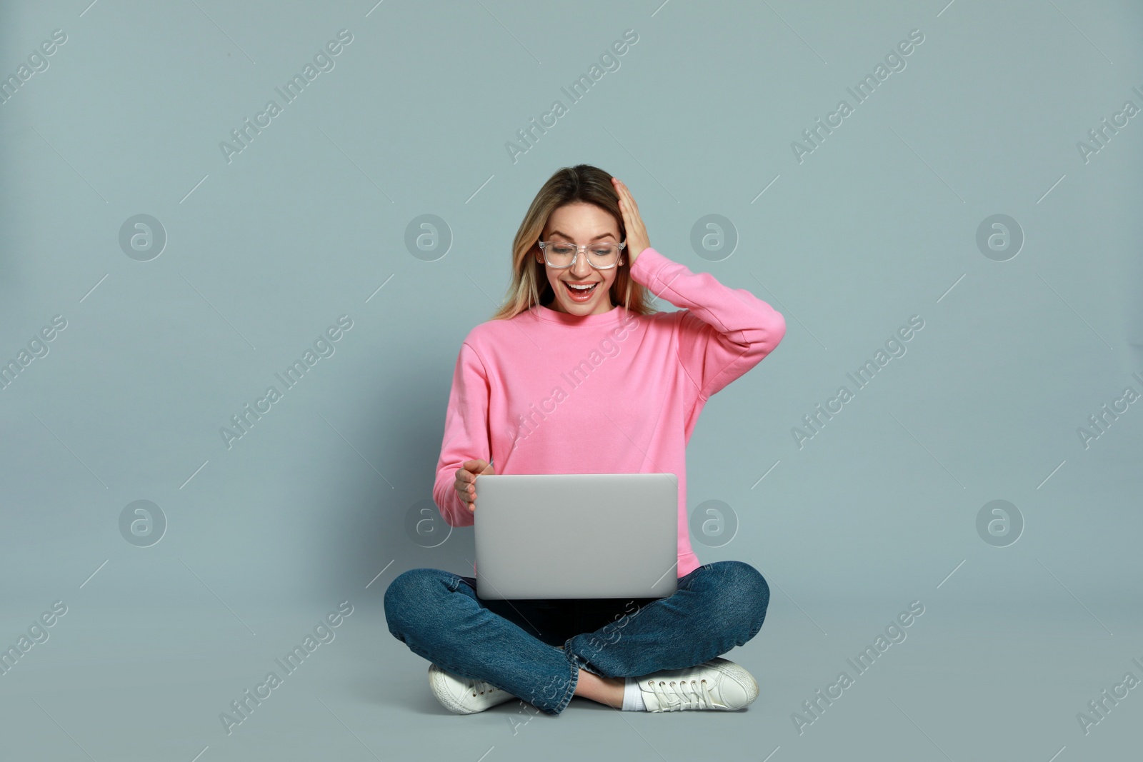 Photo of Young woman with modern laptop on grey background