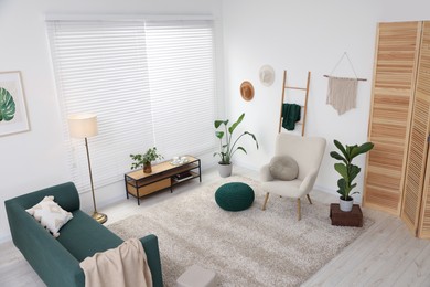 Photo of Stylish room interior with comfortable armchair, sofa and houseplants, above view