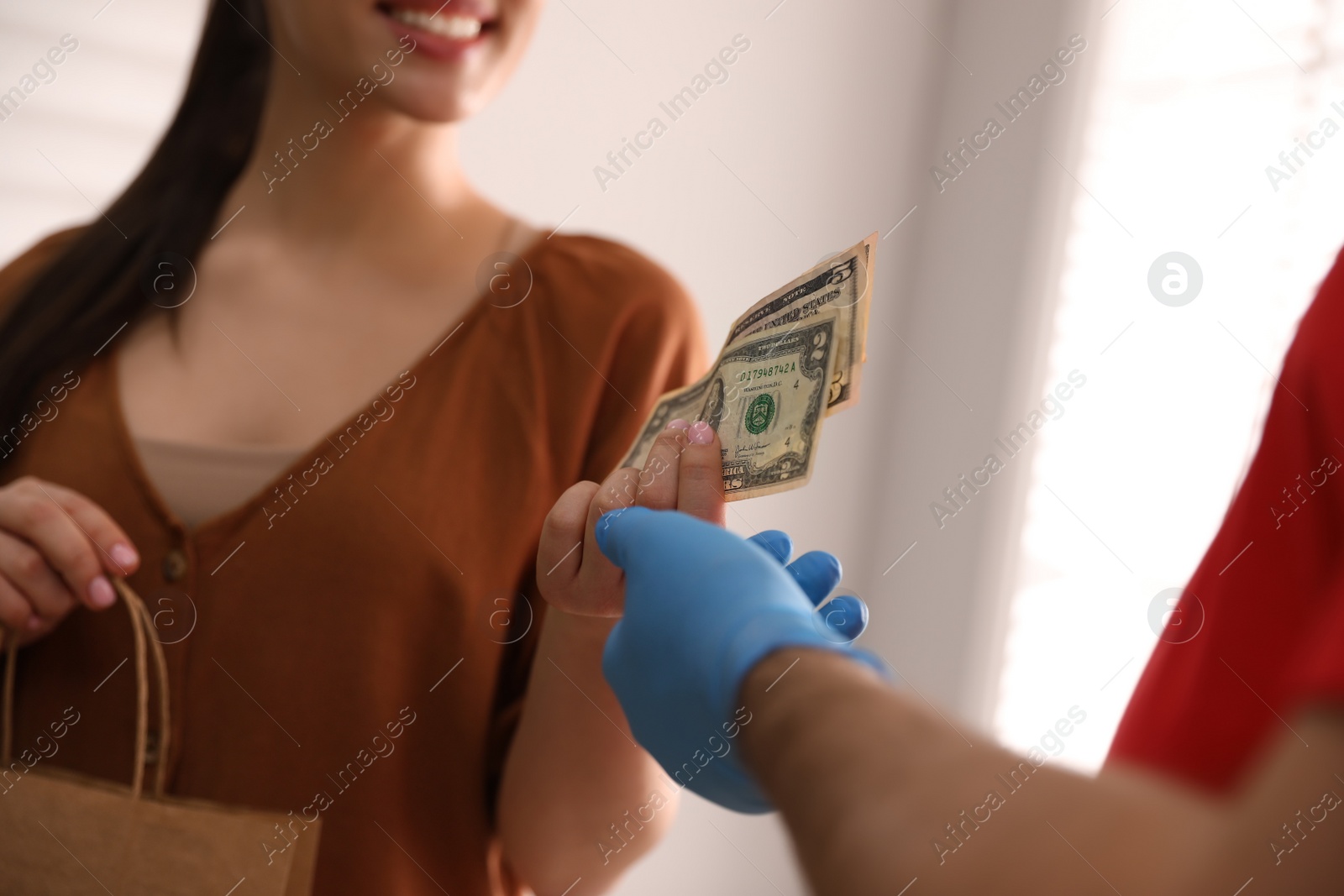 Photo of Woman giving tips to deliveryman indoors, closeup