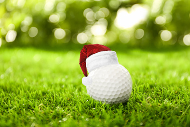 Golf ball with small Santa hat on green course