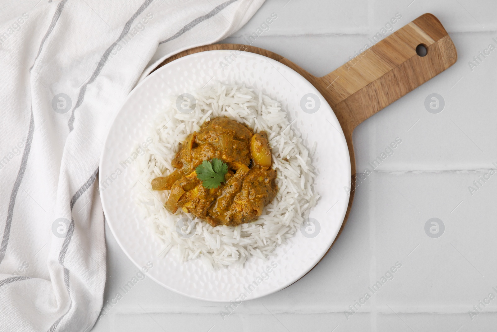 Photo of Delicious chicken curry with rice on white tiled table, top view